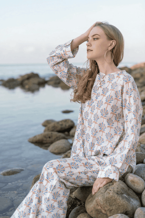 Woman in bubble-patterned dress sitting on rocks by the sea.