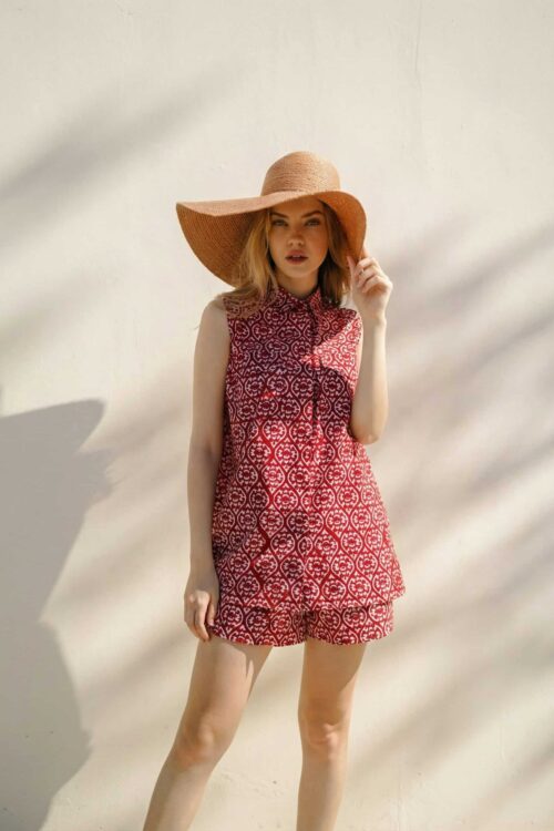 Woman in stylish red patterned summer outfit with wide-brim hat.