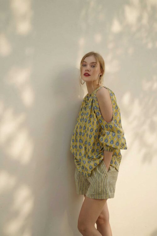 Woman in stylish yellow patterned top and striped shorts, summer fashion.