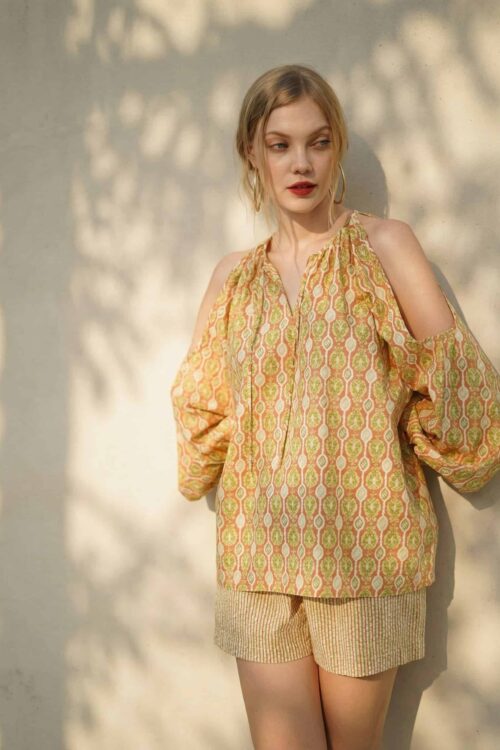 Woman wearing a patterned blouse and shorts, summer fashion for August.