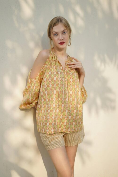 Stylish woman wearing a yellow patterned blouse and beige shorts.