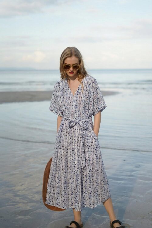 Woman in a floral beach dress walking on the shore in April.