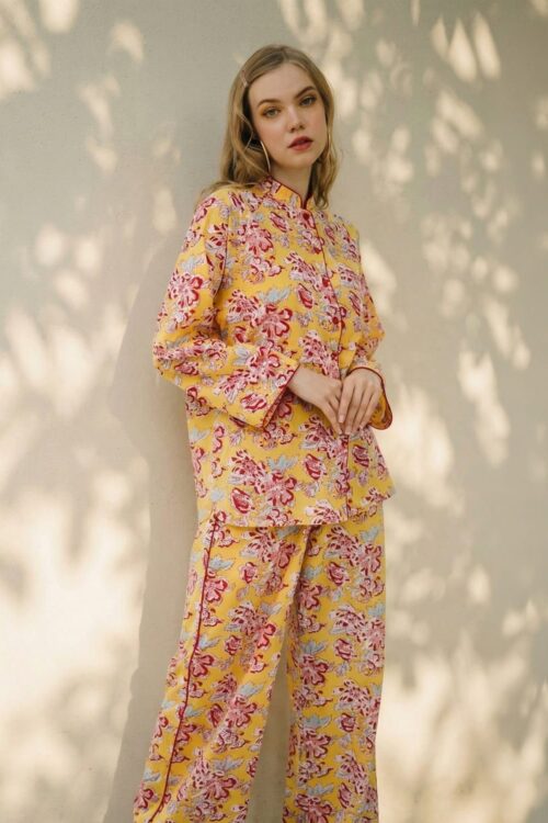 Woman wearing yellow floral pajama set with pink and purple accents.