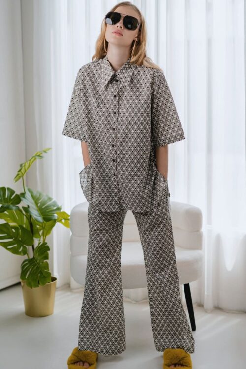 Woman wearing stylish Toffee patterned pajama set with sunglasses indoors.