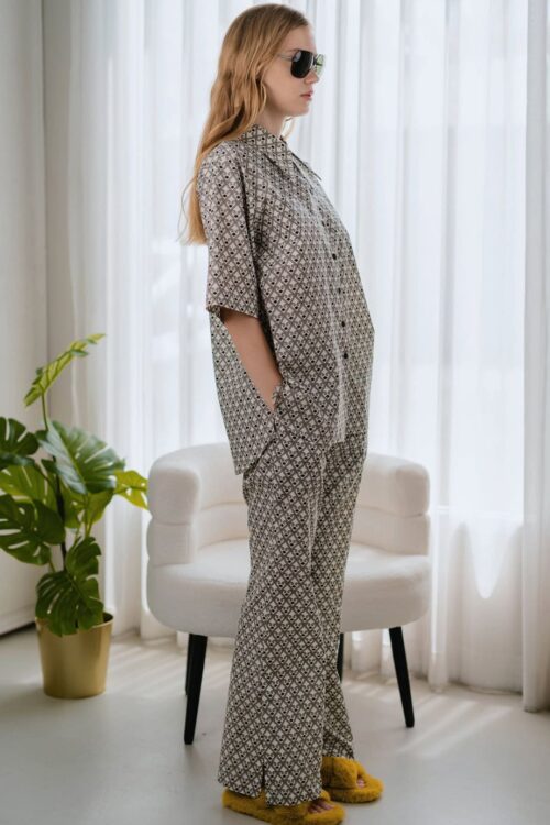 Woman in toffee-colored patterned pajamas with sunglasses indoors.