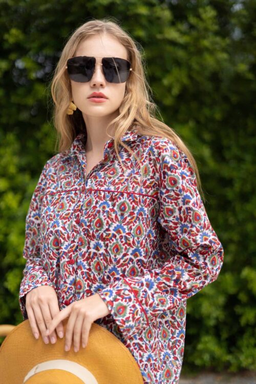 Woman wearing a vibrant, patterned shirt with sunglasses outdoors in May.