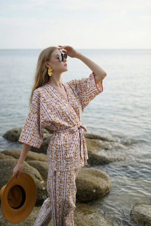 Stylish woman in patterned outfit enjoying cloudy weather by the sea.
