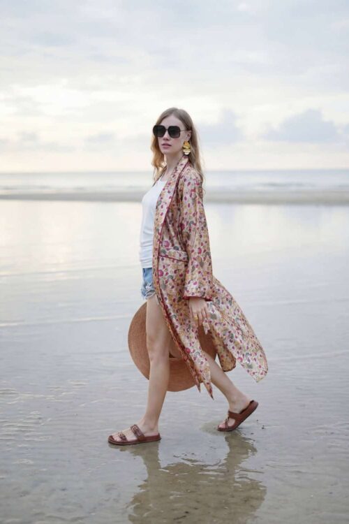 Elegant woman wearing a floral kimono and tiara at the beach.