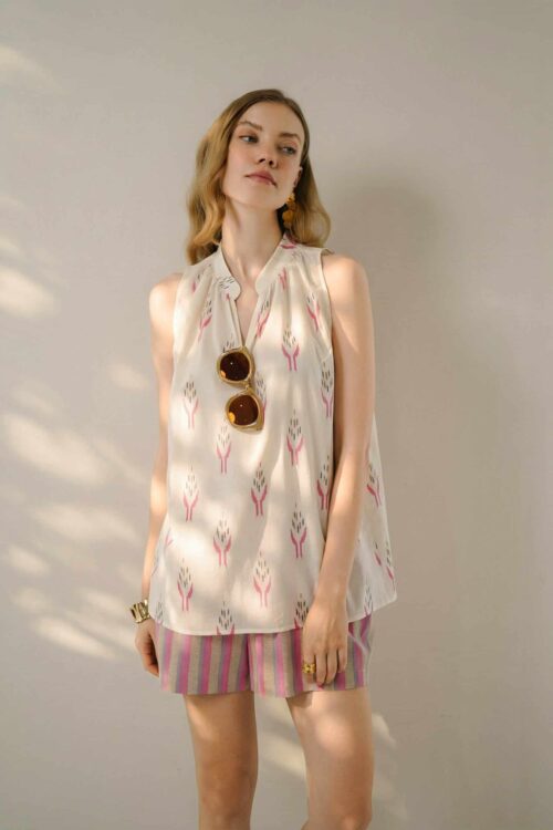 Woman wearing a sleeveless honey-themed patterned summer dress with pink accents.
