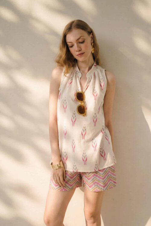 Woman in honey-colored summer outfit with patterned shorts and sleeveless top.