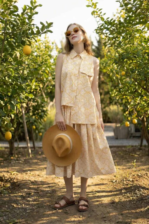 Beautiful woman in a floral dress holding a straw hat in a lemon orchard.