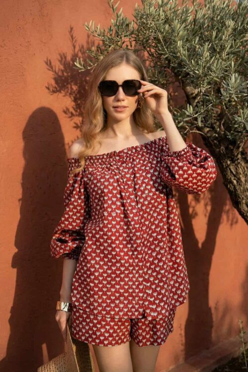 Stylish woman wearing a red carrot print off-shoulder dress with sunglasses outdoors.
